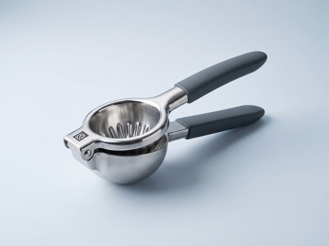 Studio photograph of the Kensington London stainless steel lemon squeezer showing the hinge pin, pressed cup, perforated strainer bowl and grey silicone grips
